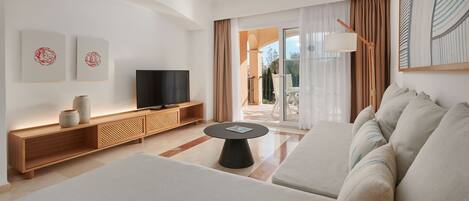 Una sala de estar moderna con un televisor de pantalla plana, un sofá, una mesa de centro y un balcón con cortinas.