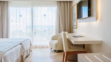 Habitación de hotel con cama, escritorio, silla, televisor y vistas de la ciudad.