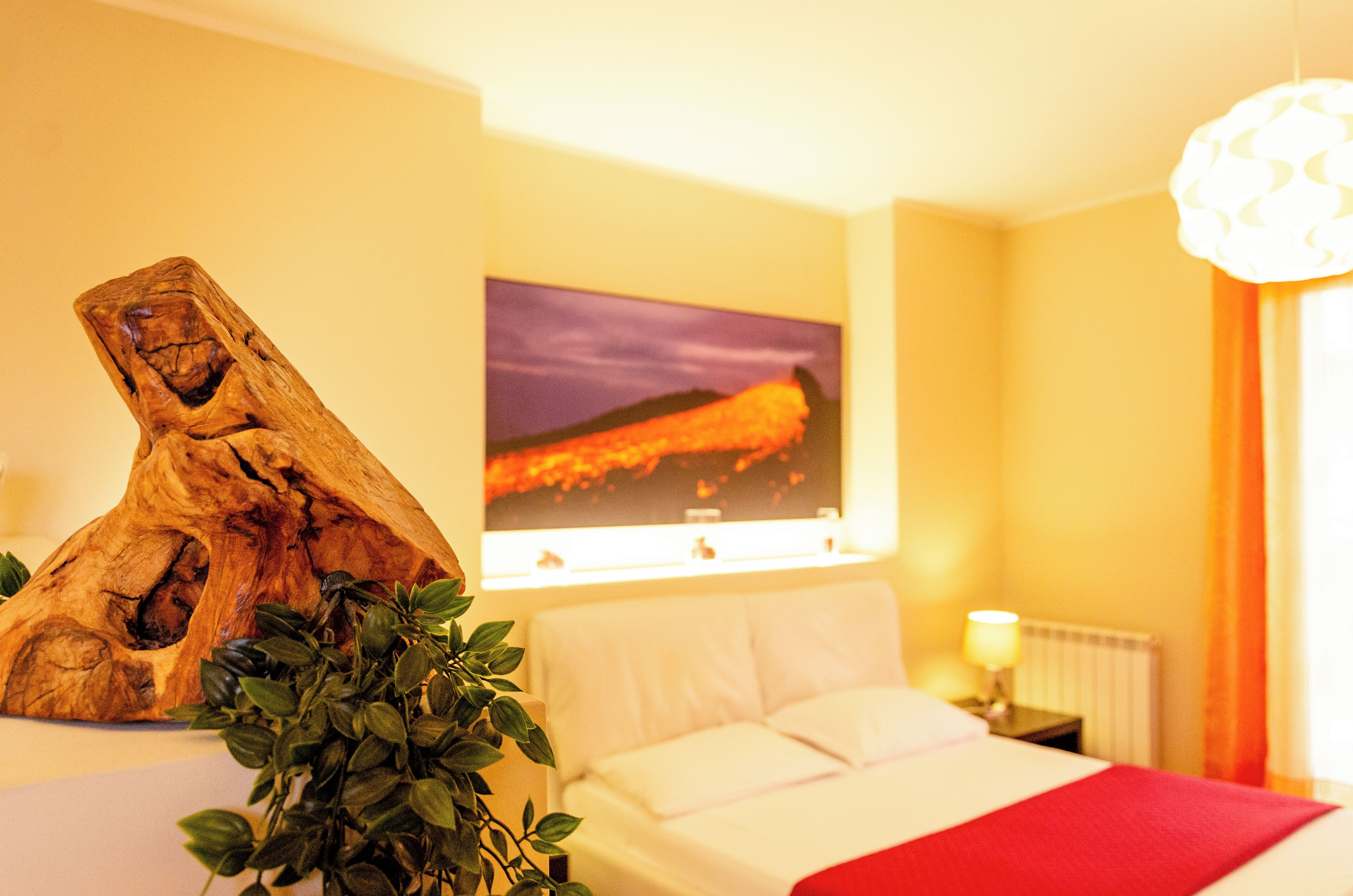 Ein Hotelzimmer mit einem Bett, einer Holzskulptur, einem Gemälde und einer Pflanze.