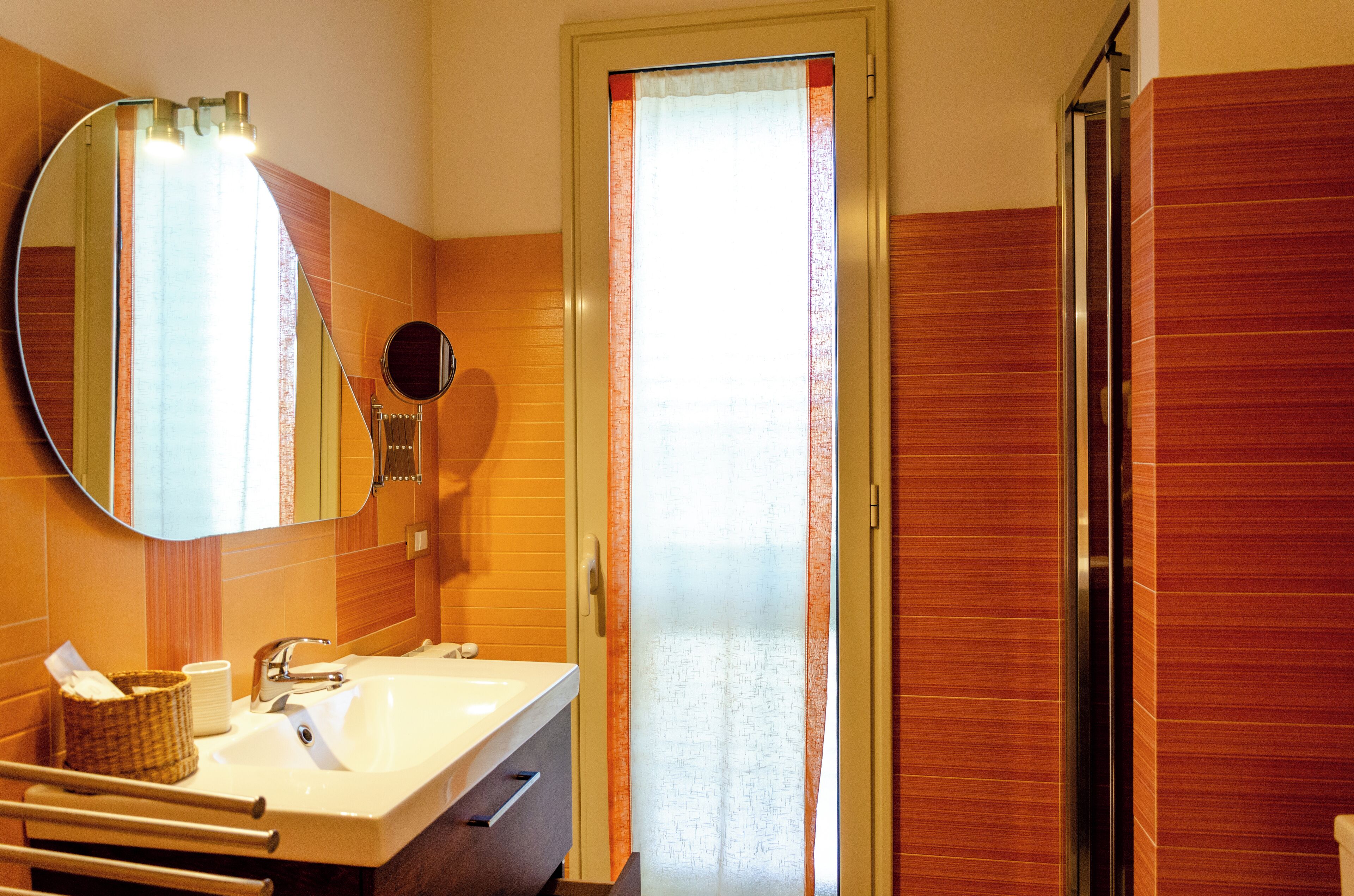 A bathroom with a large mirror, a sink, a towel rack, and a shower area.