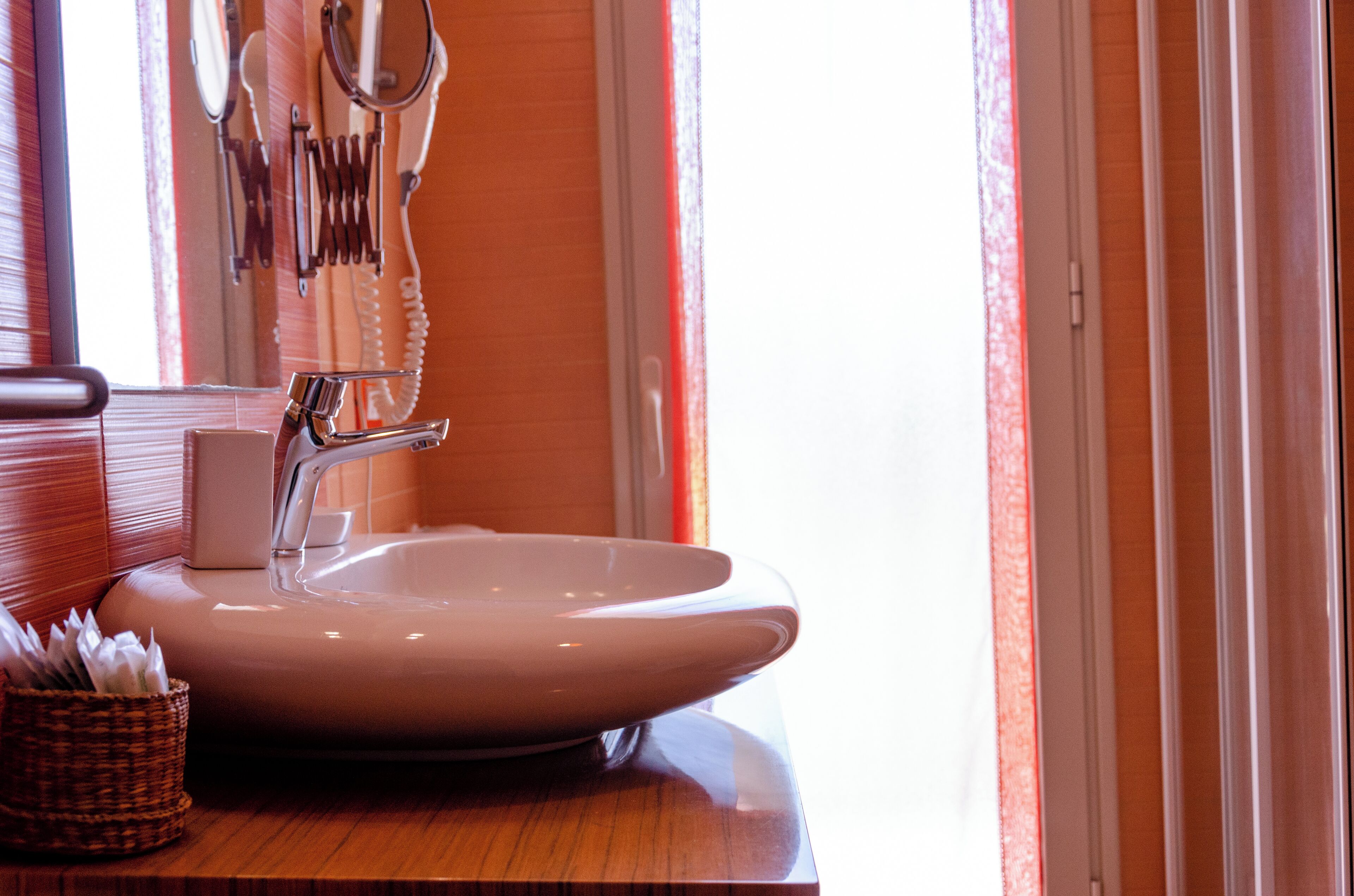 A bathroom with a large sink, a mirror, and a telephone mounted on the wall.