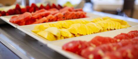 A buffet with various fruits including watermelon, mango, and tomatoes.