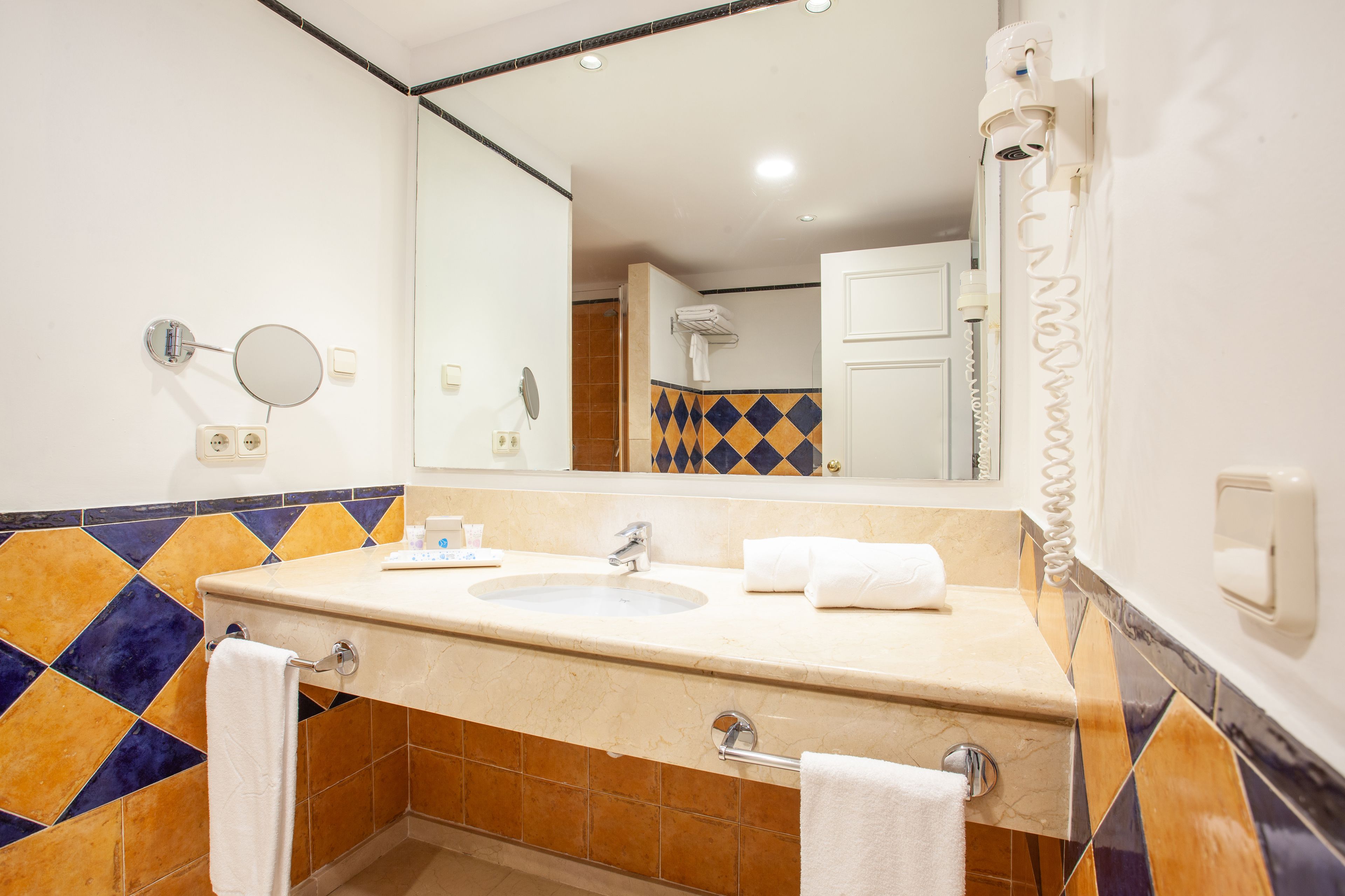 Un baño con lavamanos doble, espejo y toallero.