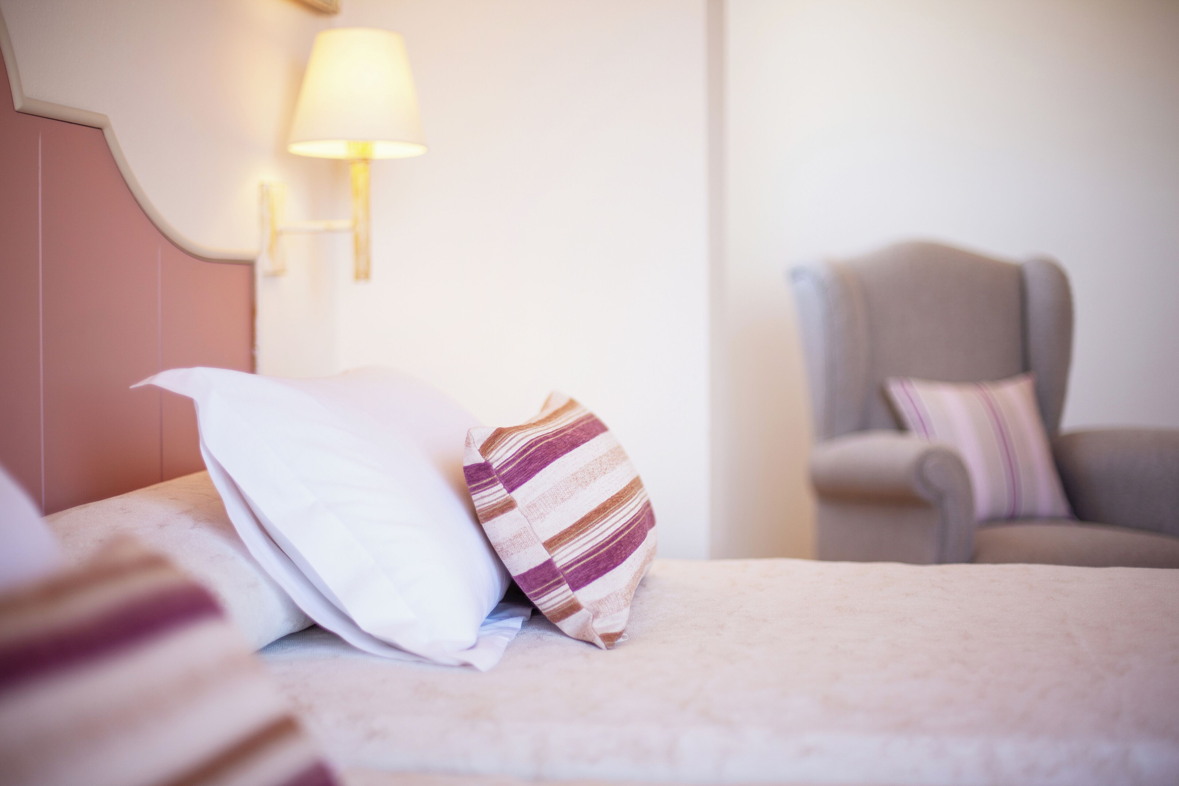 A hotel room with a bed, a lamp, and a chair.