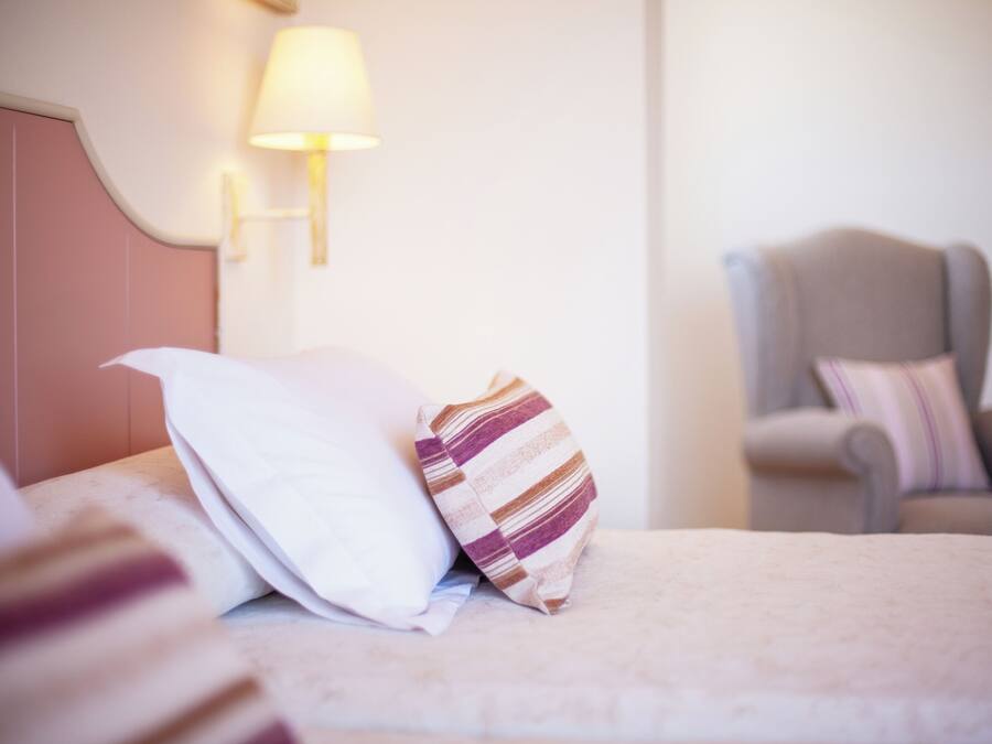 A hotel room with a bed, a lamp, and a chair.