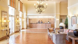Un vestíbulo amplio con mostrador de recepción, zona de estar y una araña.