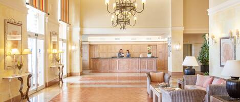 A spacious lobby with a reception desk, seating area, and a chandelier.