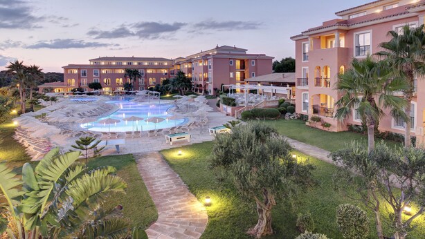 Un hotel con piscina, mobiliario exterior y un jardín bien cuidado.