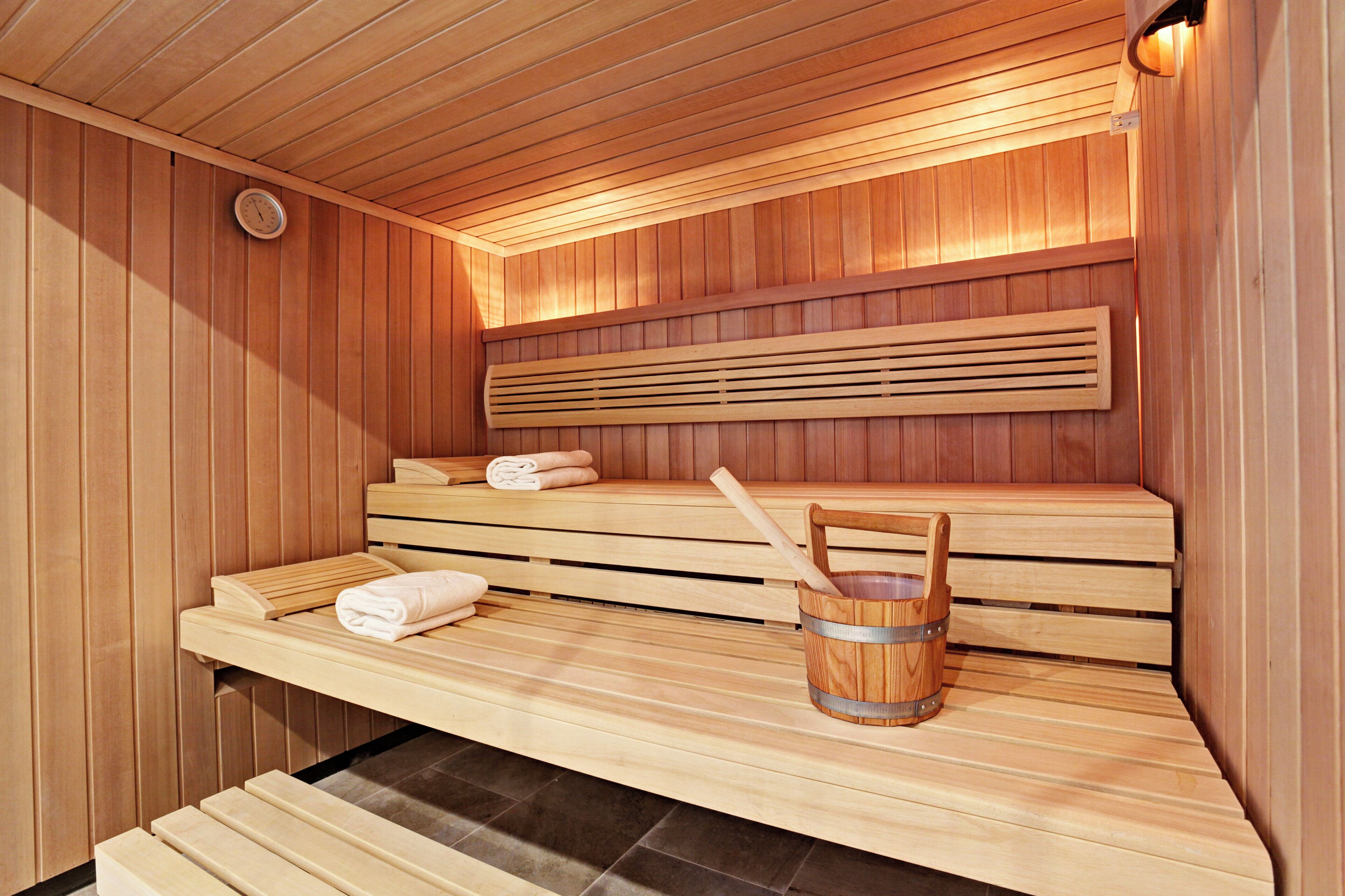 A wooden sauna with benches, a bucket, and towels.