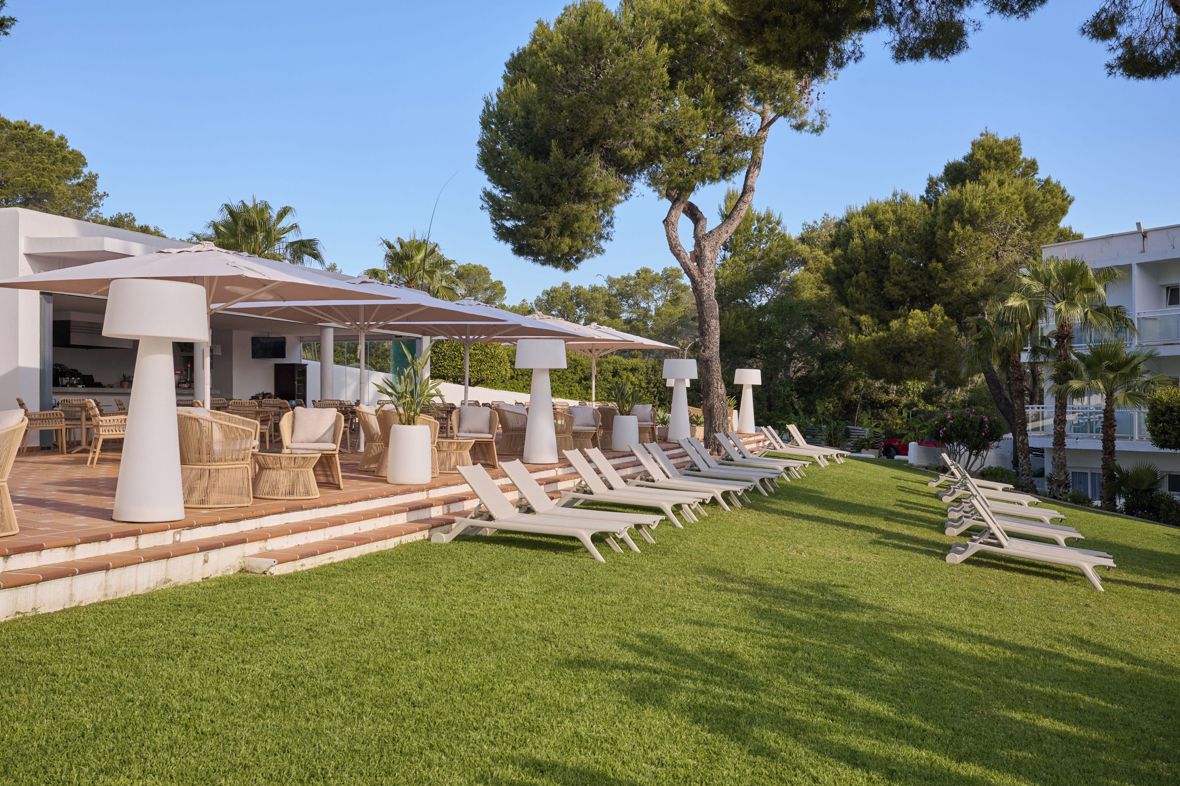 Un resort con asientos al aire libre, zona de piscina y un edificio de diseño moderno.