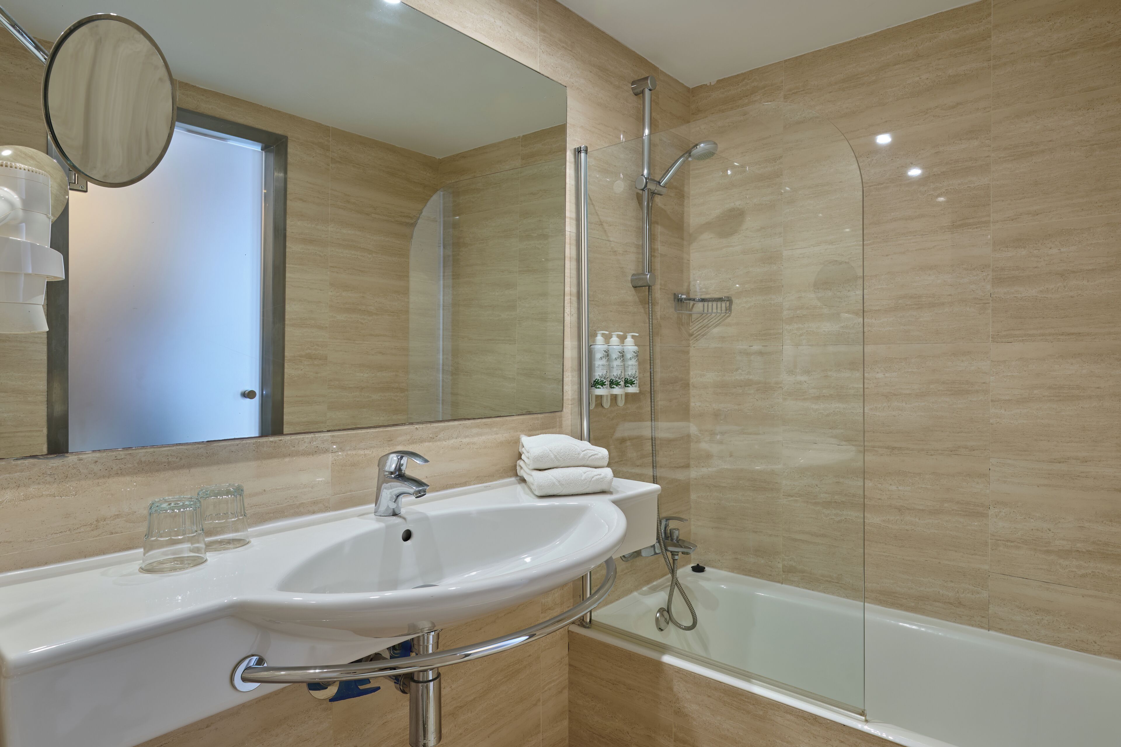 Une salle de bain avec un lavabo blanc, un miroir, une douche en verre et un porte-serviettes.