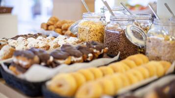 Een buffet met diverse soorten eten, zoals gebak, ontbijtgranen en chocolade lekkernijen.