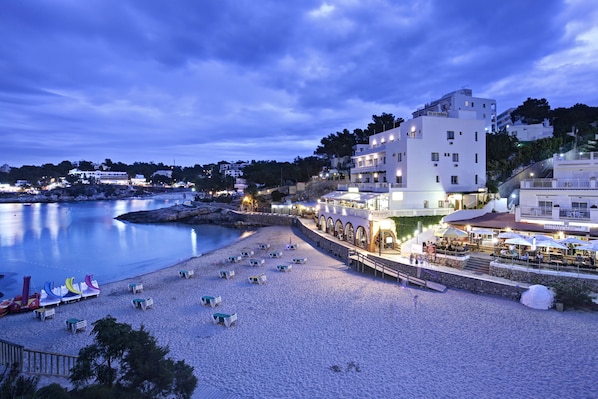 Un hotel frente a la playa con piscina, terraza y restaurante.