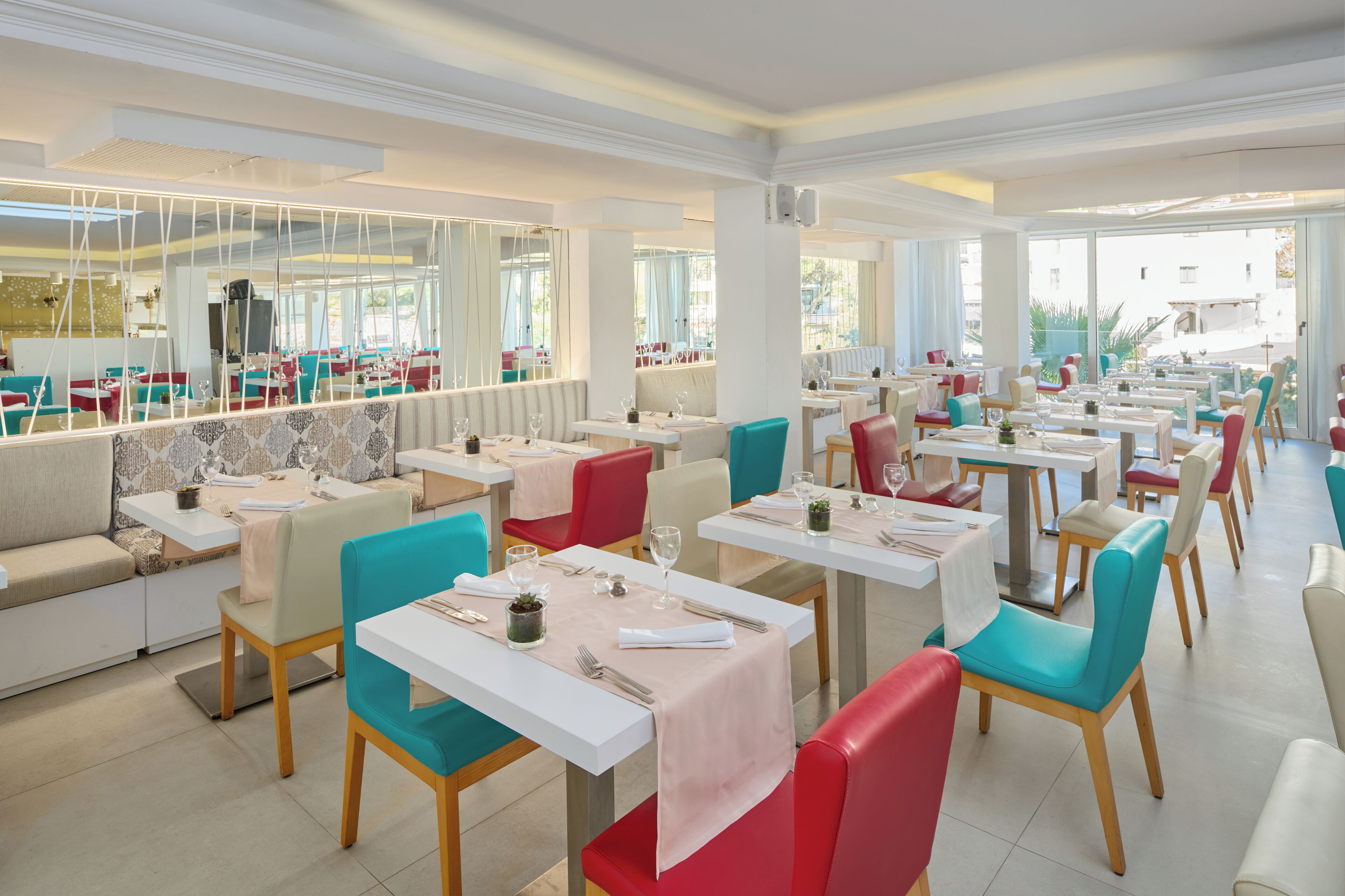 Un restaurante con varias mesas y sillas, ventanas amplias y una decoración interior moderna.