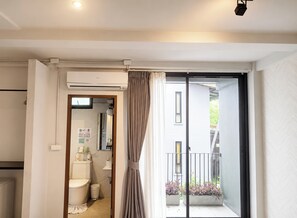 A modern bathroom with a toilet, sink, and shower, a balcony with plants, and a sliding glass door to the outside. - Palmari Boutique Hotel (Nuea Khlong)