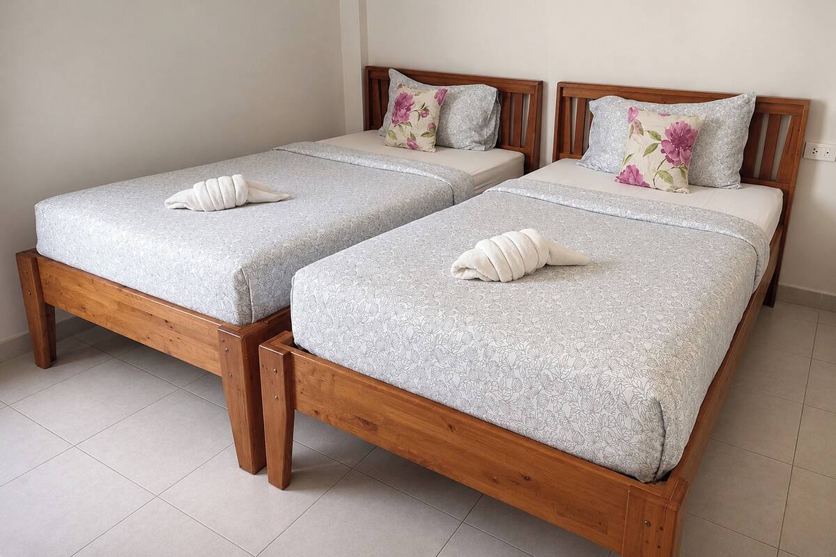 Twee houten bedden met beddengoed en handdoeken met bloemenprint.