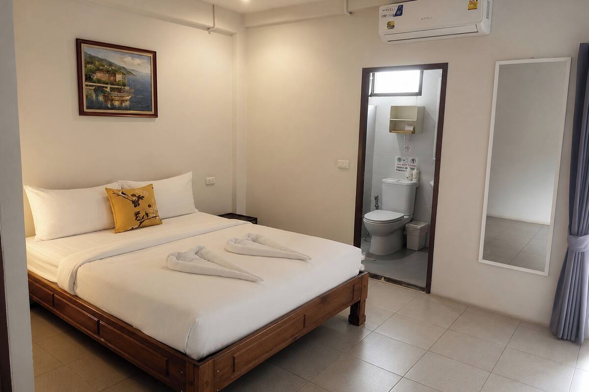 Een hotelkamer met een bed, een schilderij, een badkamer en een airconditioning.