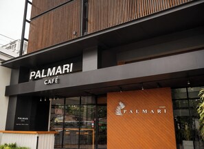 A modern building with a sign reading 'PALMARI CAFE' and a logo with a palm tree. - Palmari Boutique Hotel (Nuea Khlong)