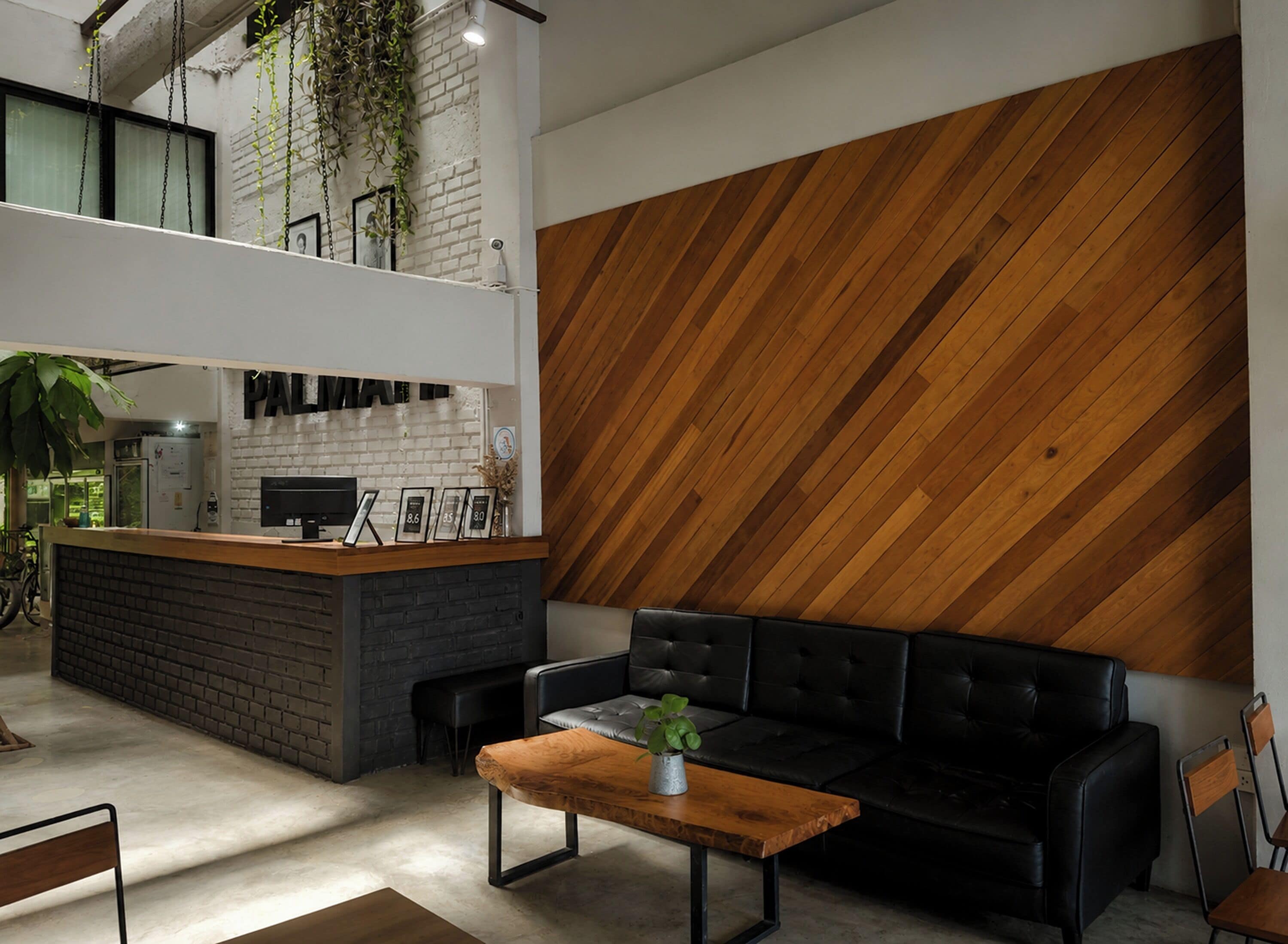 Un intérieur moderne avec un comptoir d’accueil, un canapé en cuir noir et un mur d’accent en bois.