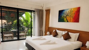 A hotel room with a large bed, a view of greenery through a sliding door, and a painting on the wall. - Palmari Boutique Hotel (Nuea Khlong)