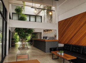 Eine moderne Hotelhalle mit Rezeption, Sitzgelegenheiten und einer großen Zimmerpflanze.