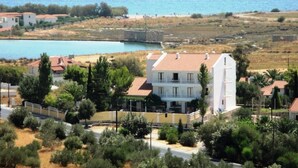 Ein Küstengebäude mit rotem Ziegeldach, umgeben von Grün und Blick aufs Meer.