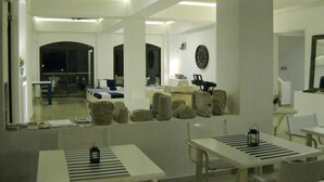 Eine moderne Hotellobby mit einer zentralen Sitzecke, einem Empfangstresen und einem großen Fenster mit Blick auf die Straße.