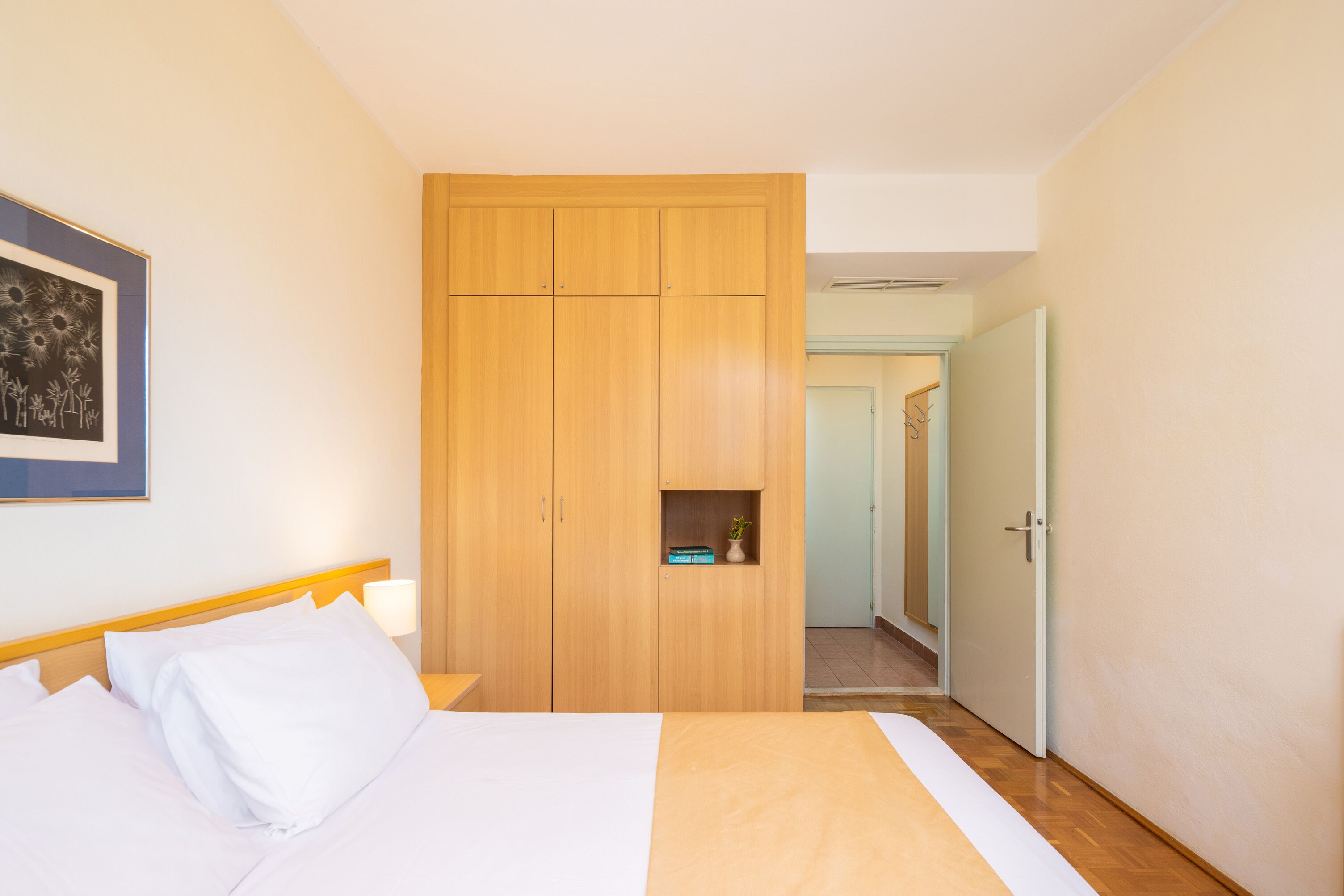 Een hotelkamer met een bed, een houten kledingkast en een klein plankje met een plant.