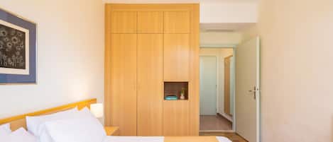 Een hotelkamer met een bed, een houten kledingkast en een klein plankje met een plant.