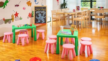 Ein Spielzimmer für Kinder mit Holztischen, rosafarbenen Hocker und Lernspielzeug.