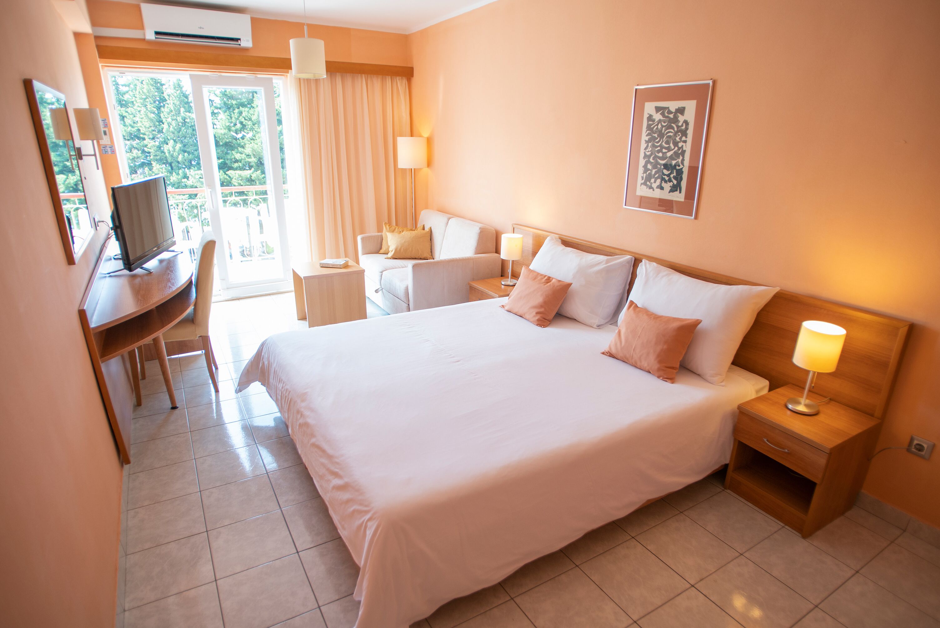 A hotel room with a large bed, a desk, a chair, a TV, and a window with curtains.
