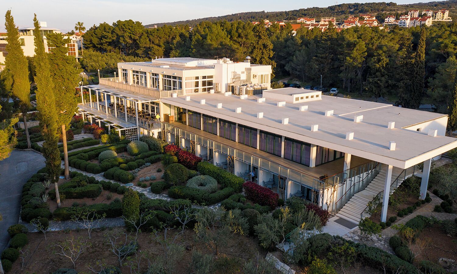 A modern building with a flat roof, large windows, and a covered outdoor area with seating.