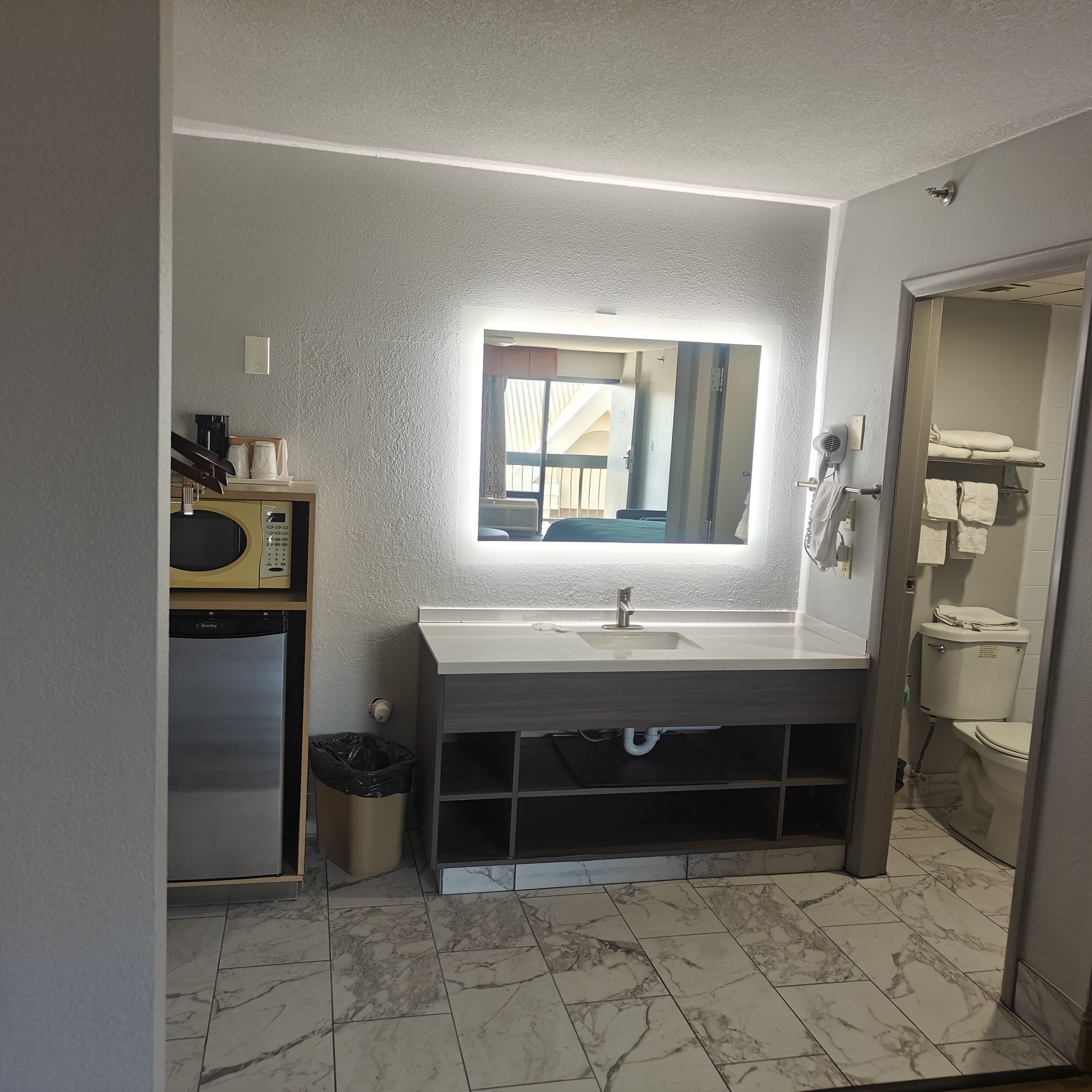 Un baño moderno con piso de mármol, un espejo grande y un lavamanos.