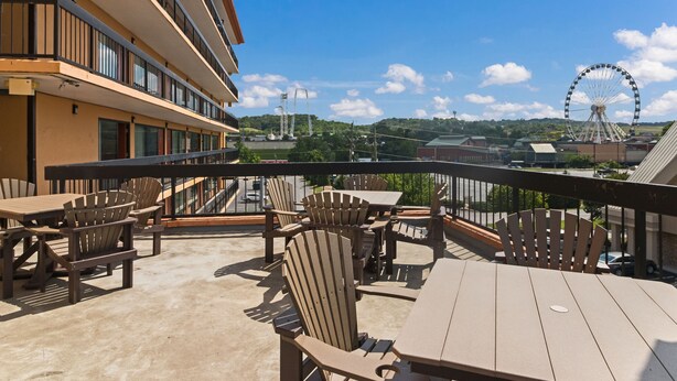 A balcony with outdoor seating, a view of a Ferris wheel, and a building in the background. - Mountain Vista Inn & Suites (Pigeon Forge)