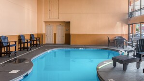 An indoor swimming pool with blue tiles, surrounded by chairs and a bench. - Mountain Vista Inn & Suites (Pigeon Forge)