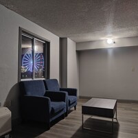 A modern living room with a dark blue sofa, a small coffee table, and a large window displaying a Ferris wheel.