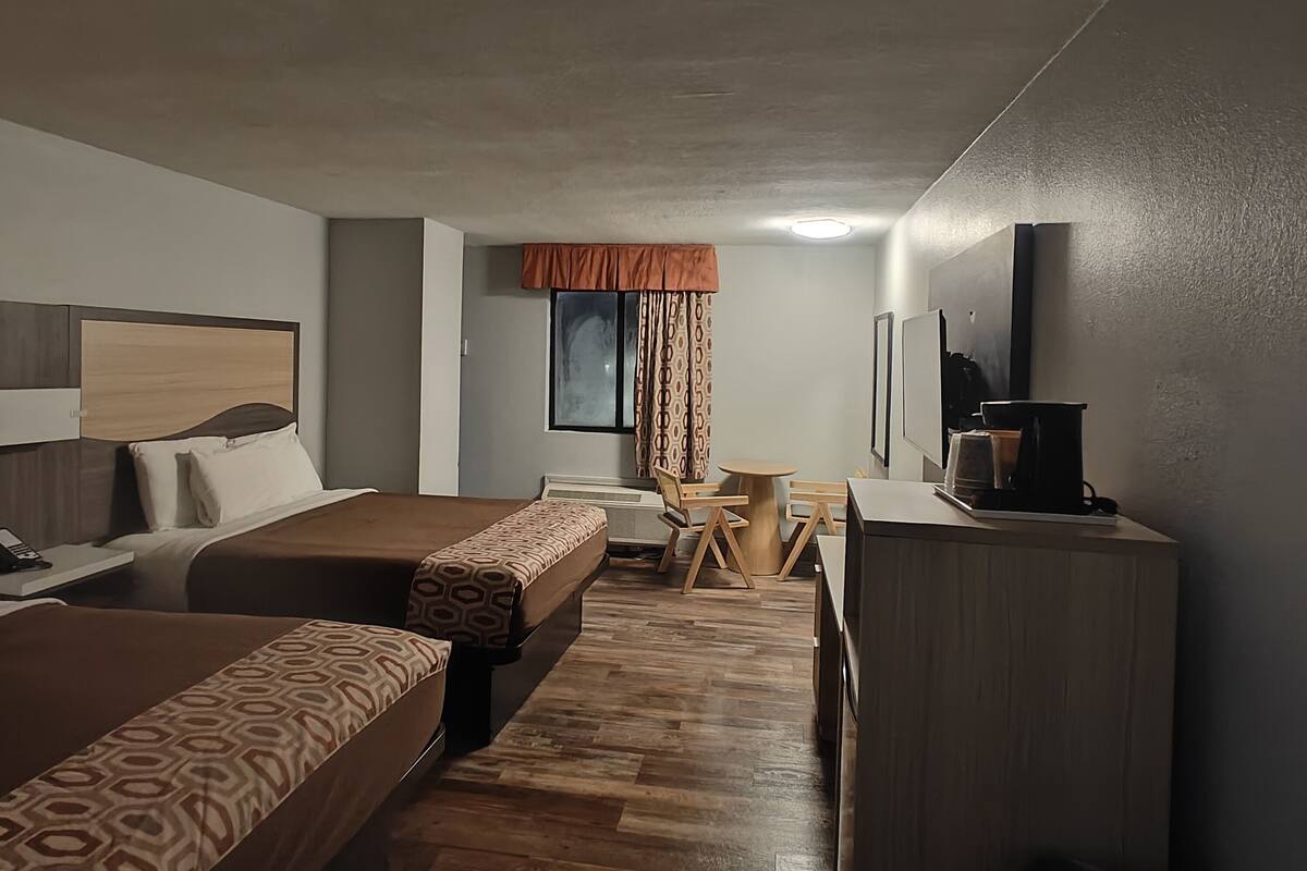 A compact hotel room with a bed, a desk, and a chair.