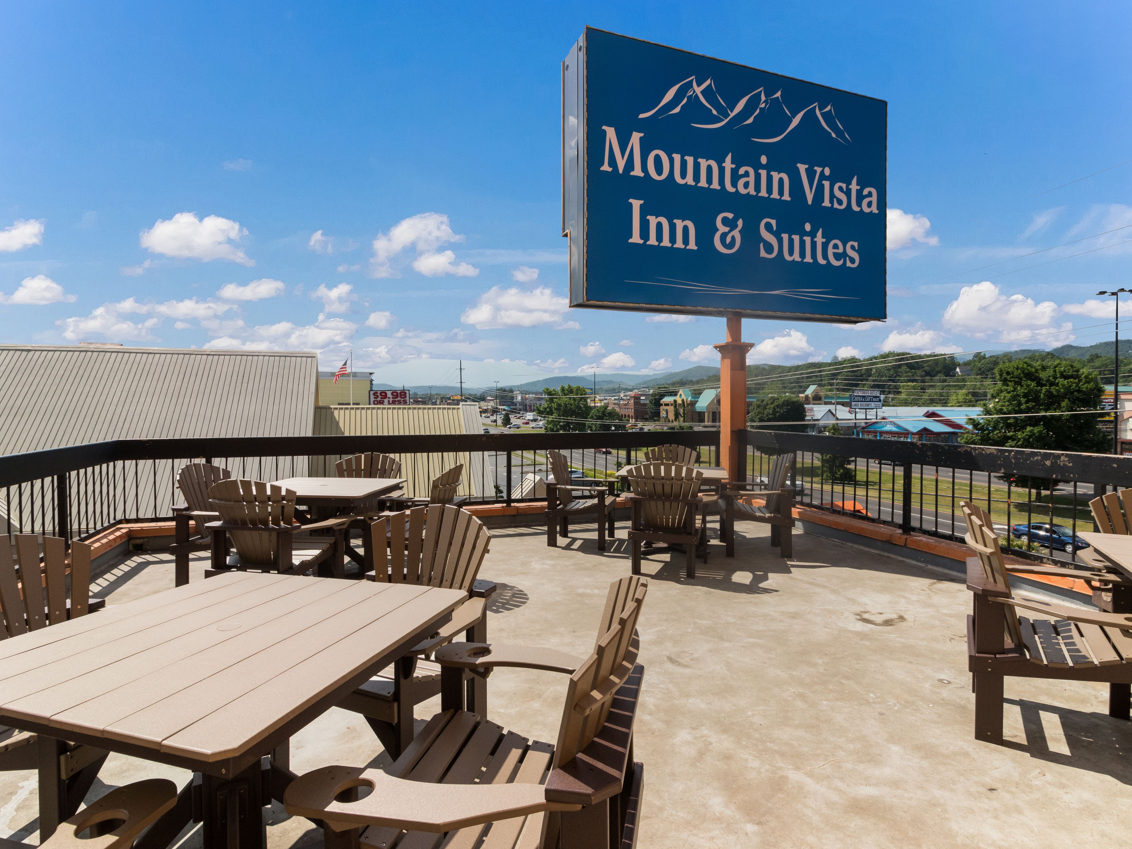 Außenbereich des Mountain Vista Inn & Suites mit Tischen und Stühlen, mit Blick auf einen Parkplatz und Gebäude.