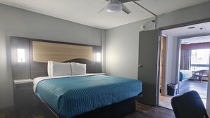 A bedroom with a bed, a ceiling fan, a door leading to a balcony, and a chair. - Mountain Vista Inn & Suites (Pigeon Forge)