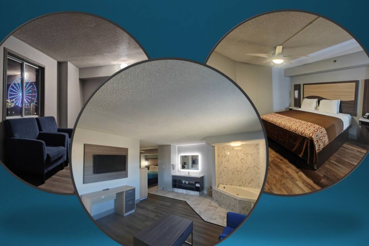 A hotel room with a bed, a desk, a chair, a TV, a bathroom with a mirror, and a view of a Ferris wheel.