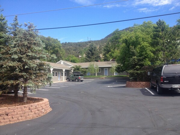 A parking lot with a building in the background, surrounded by trees.