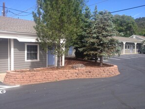 A building with a brick planter and trees, a parking lot, and a clear sky.