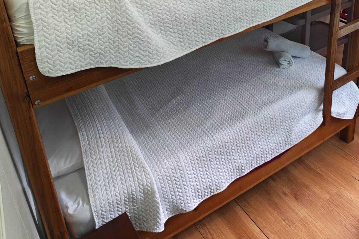 Una cama litera con un colchón blanco acolchado y una litera inferior con un colchón sencillo.