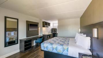 A hotel room with a bed, a desk, a chair, a TV, and a phone.