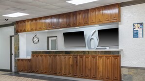 A reception area with wooden paneling, a clock, and a large number '6' sign. - Motel 6 Stockbridge, GA – Hwy 138 W (Stockbridge)