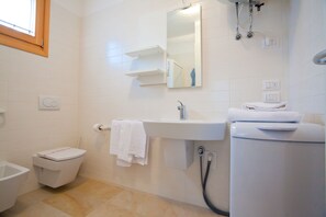 A modern bathroom with a toilet, sink, and shower. - Villaggio Laguna Blu (Caorle)