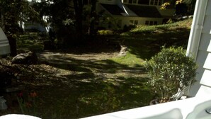 A hot tub with two glasses of water, a towel, and a view of a house and garden. - Chestnut Lodge (Lee)