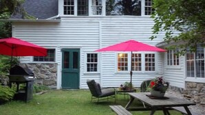 A white house with a stone foundation, a green door, and a patio with a table and chairs. - Chestnut Lodge (Lee)
