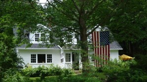 A white house with a porch and an American flag. - Chestnut Lodge (Lee)