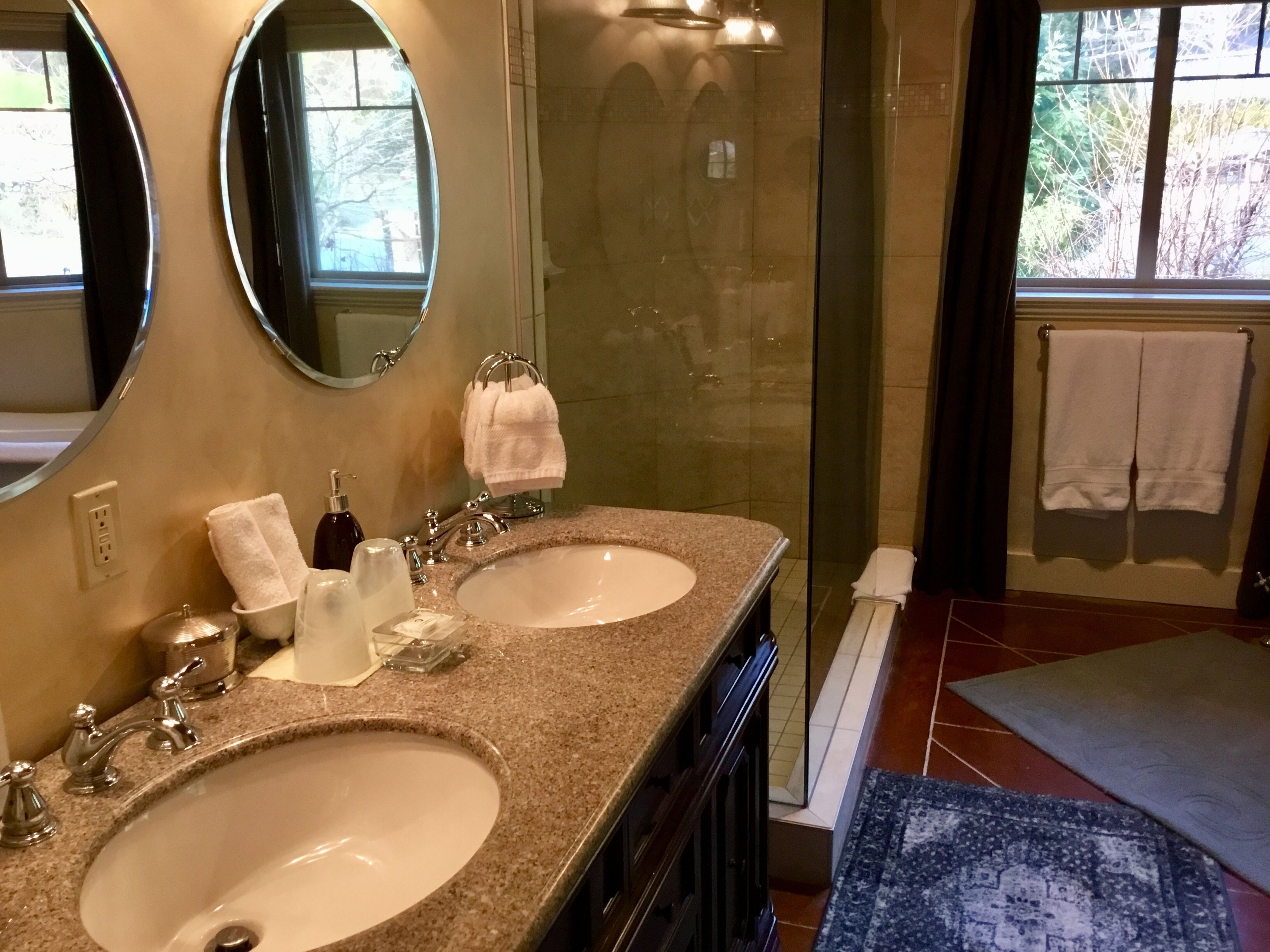 A bathroom with two sinks, a large mirror, and a glass shower enclosure.